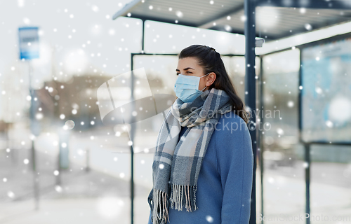 Image of young woman wearing medical mask at bus stop