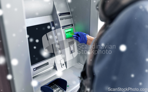 Image of woman in medical glove with credit card at atm