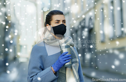 Image of woman in reusable mask with tumbler in city