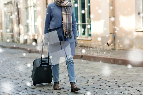 Image of woman with travel bag walking along empty street