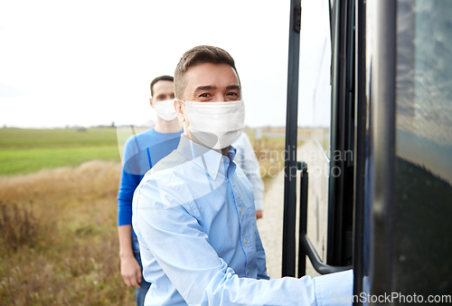 Image of group of passengers in masks boarding travel bus