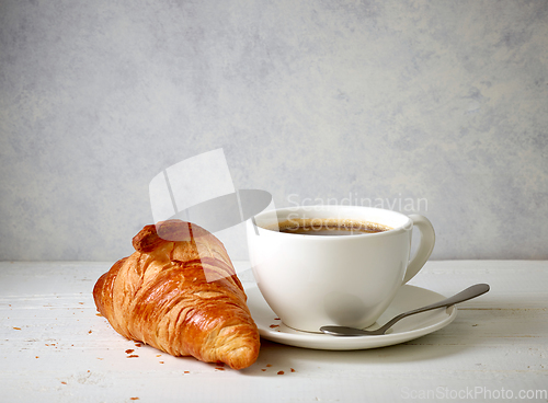 Image of freshly baked croissant and cup of coffee