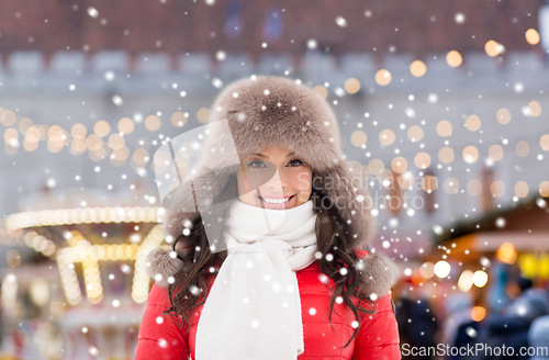 Image of happy woman in winter hat over christmas market