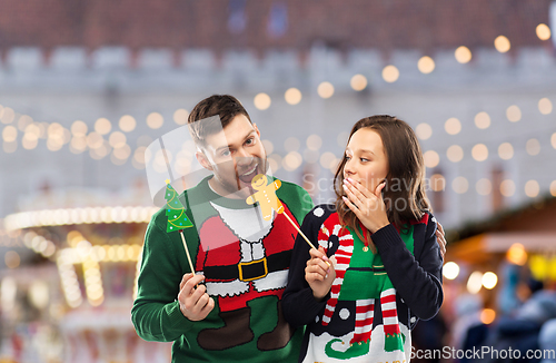 Image of couple with christmas party props in ugly sweaters