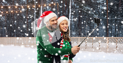 Image of happy couple in christmas sweaters taking selfie