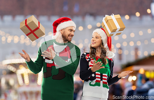 Image of happy couple in christmas sweaters with gifts