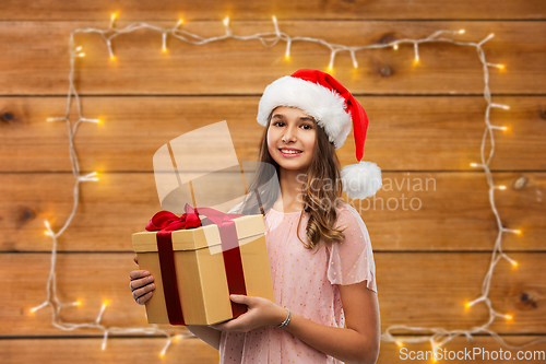 Image of teenage girl in santa hat with christmas gift