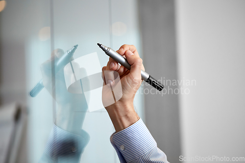 Image of hand with marker and sticker on glass at office