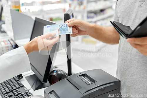 Image of pharmacist taking money from customer at pharmacy