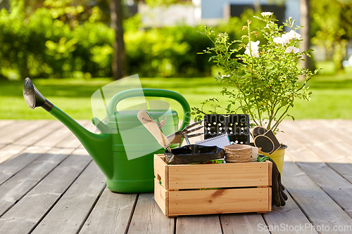 Image of box with garden tools and watering can in summer