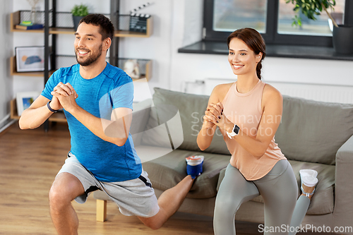 Image of happy couple exercising and doing squats at home