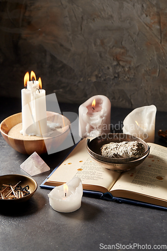 Image of magic book, sage, burning candles and ritual staff