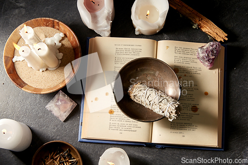 Image of magic book, sage, burning candles and ritual staff