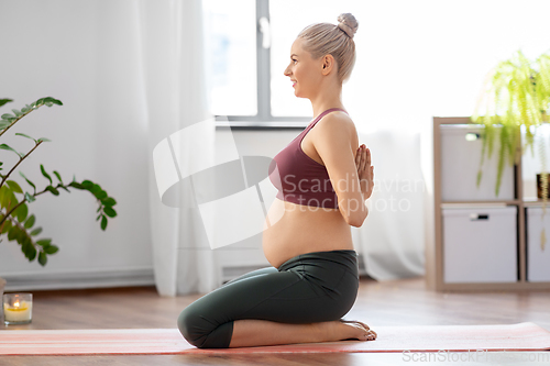 Image of happy pregnant woman doing yoga at home