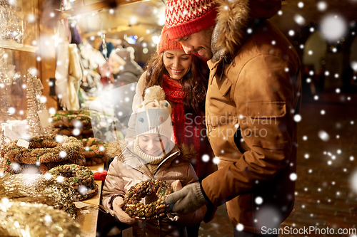 Image of happy family buying wreath at christmas market