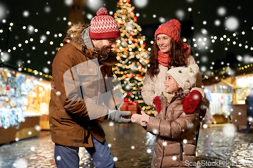 Image of happy family with gift at christmas market in city