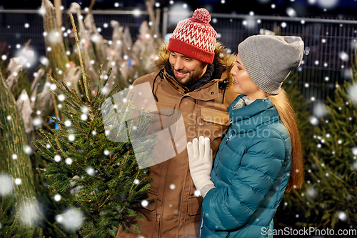Image of happy couple buying christmas tree at market