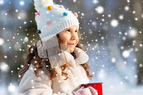 Image of little girl with cup of hot tea in winter park