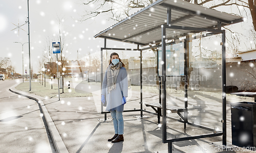 Image of young woman wearing medical mask at bus stop