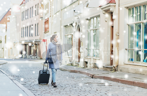 Image of woman in protective mask with travel bag in city