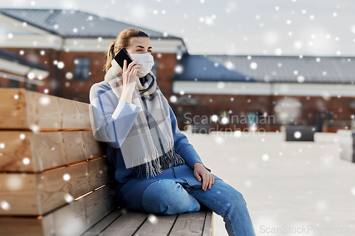 Image of woman in face mask calling on smartphone in city