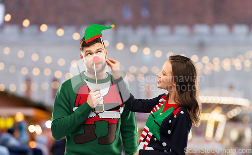 Image of couple with christmas party props in ugly sweaters