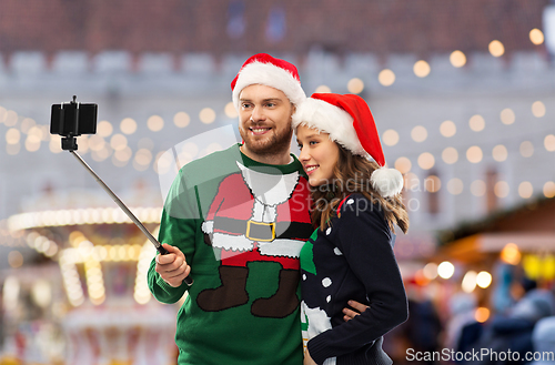 Image of happy couple in christmas sweaters taking selfie