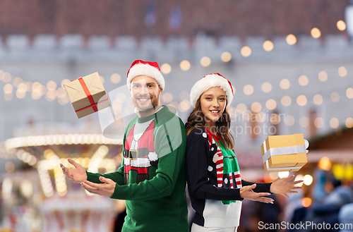 Image of happy couple in christmas sweaters with gifts