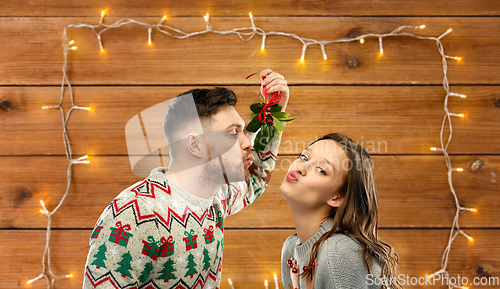 Image of happy couple kissing under mistletoe on christmas