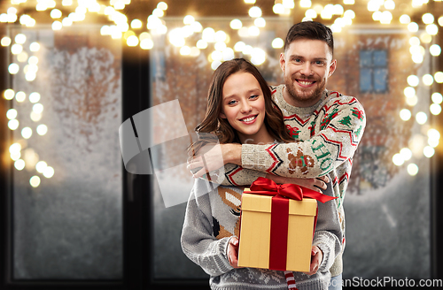 Image of happy couple in christmas sweaters with gift box