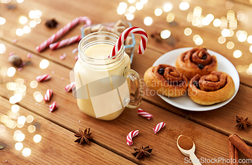 Image of eggnog with candy cane in mug and cinnamon buns