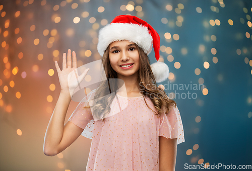 Image of happy teenage girl waving hand on christmas