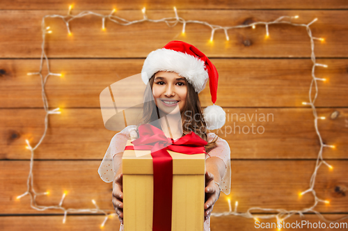 Image of teenage girl in santa hat with christmas gift