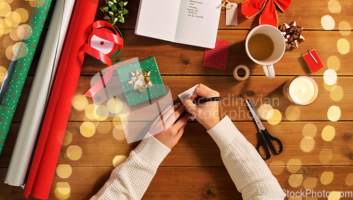 Image of hands attaching name tag to christmas gift