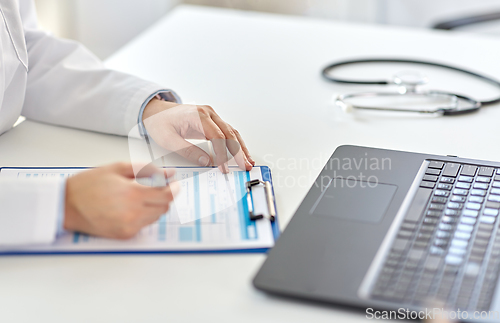 Image of doctor with laptop and medical report at hospital