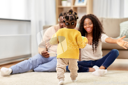 Image of african family playing with baby daughter at home