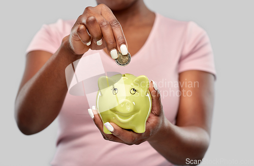 Image of close up of woman with coin and piggy bank