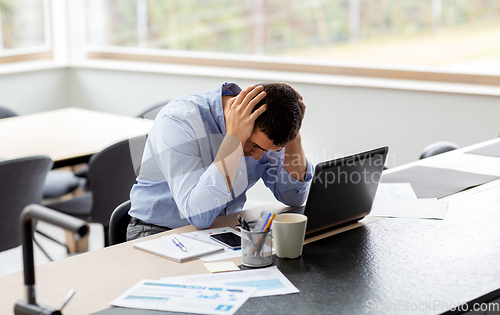 Image of stressed man with laptop working at home office