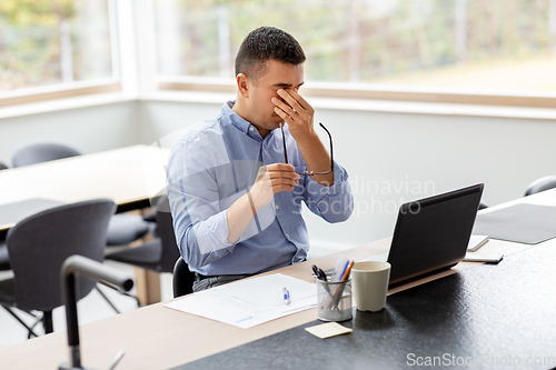 Image of tired man with laptop working at home office
