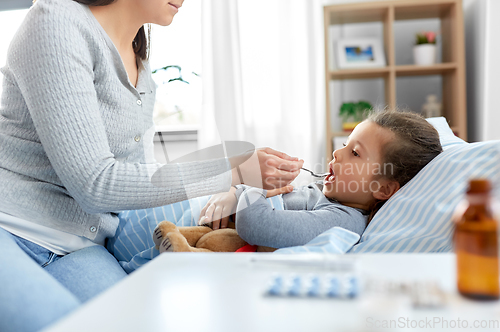 Image of mother giving cough syrup to sick daughter