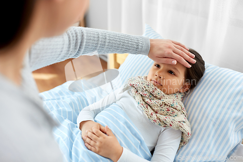 Image of mother measuring temperature of sick daughter