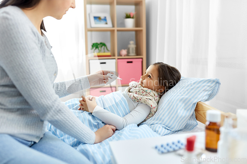 Image of mother measuring temperature of sick daughter