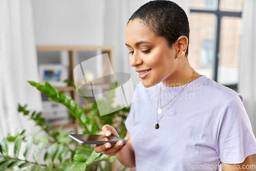 Image of african american woman with smartphone at home