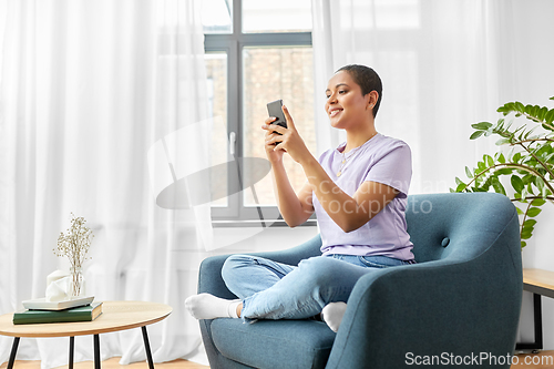 Image of african american woman with smartphone at home
