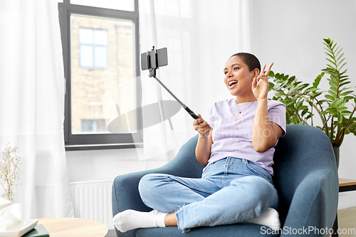 Image of happy african american woman taking selfie at home