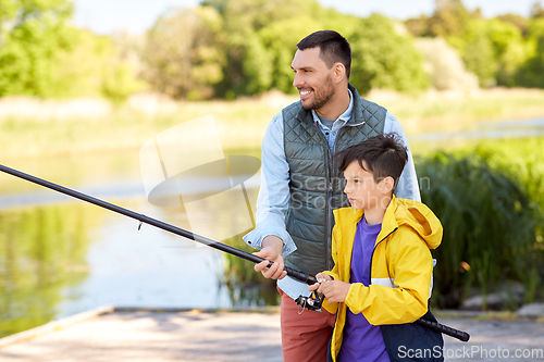 Image of happy smiling father and son fishing on river