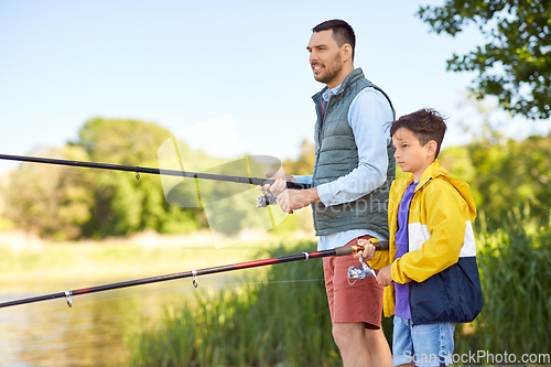 Image of happy smiling father and son fishing on river