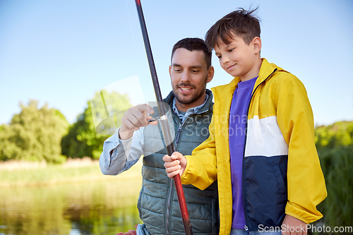 Image of happy smiling father and son fishing on river