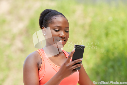Image of sporty african woman using smartphone outdoors