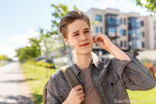 Image of young man with earphones and backpack in city